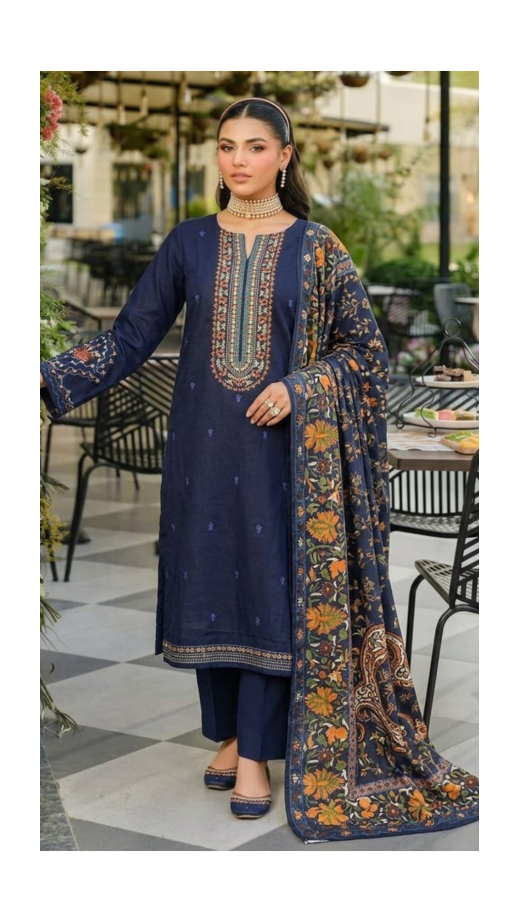 Woman wearing a navy blue embroidered outfit with a matching dupatta in an outdoor setting.
